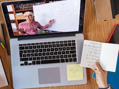 学生的桌子上有笔记本电脑和数学笔记.